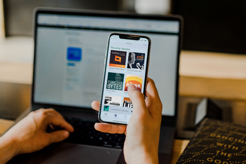person holding phone and viewing podcasts