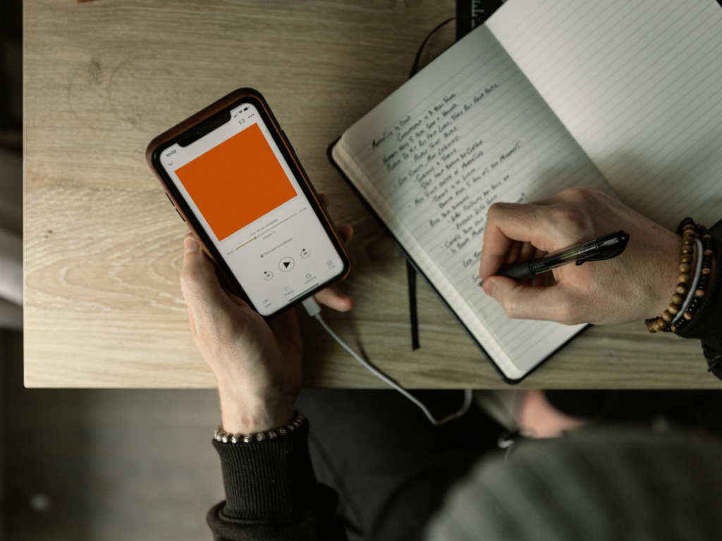 Person listening to a podcast and taking notes